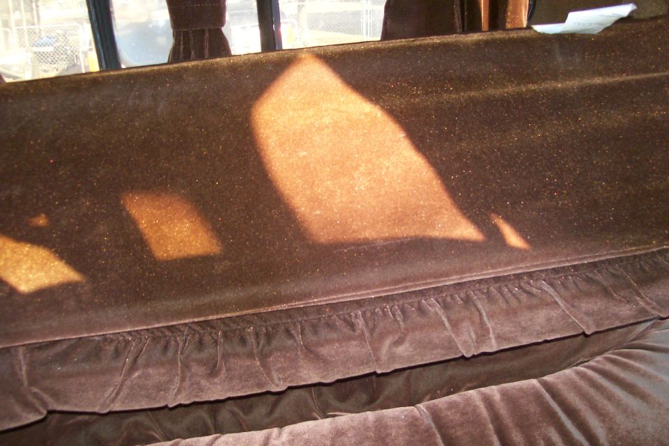 Brown velour seat interior with ruffled trim and sunlight shadows.