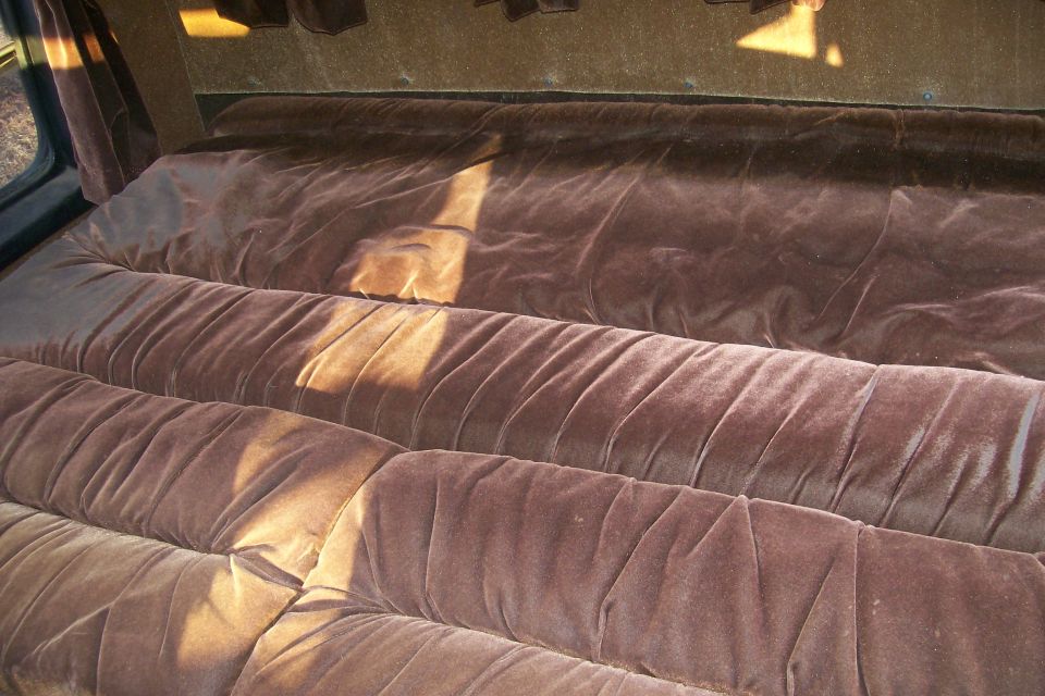Brown velour bench seat with tufting in a vehicle interior.