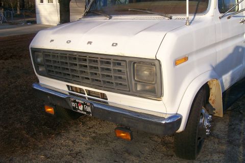 1982 Ford E350 - This Ford Econoline van features a prominent grille and a custom license plate, with a building visible in the background.