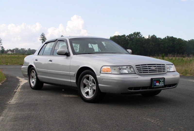 Silver 2001 Ford Crown Victoria parked on a road with trees in the background