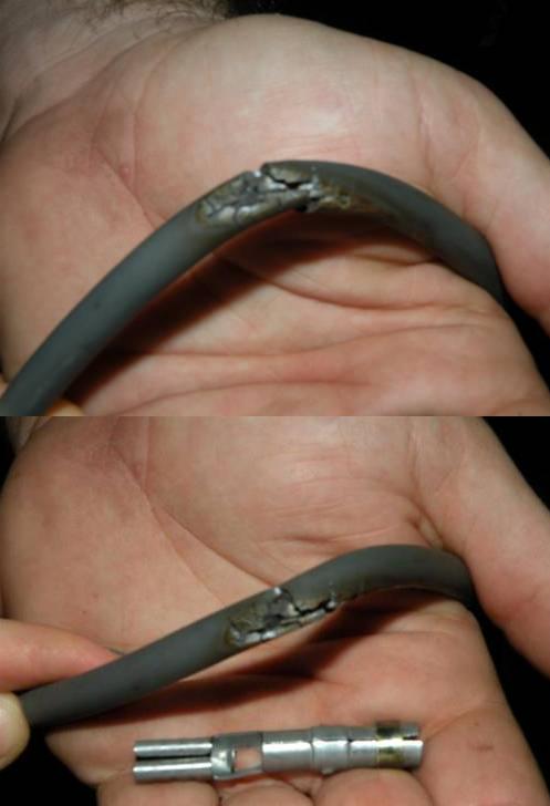 Burnt, melted gray cable held in hand with a metal splice connector shown below