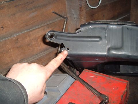 1990 Ford Ranger - A close-up view of a person's finger pointing to a small hole on a black metal automotive part, possibly a frame component. The part is mou…