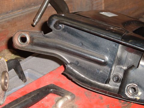 1990 Ford Ranger - A close-up view shows a black metal bracket with a circular opening and a bolt attached, resting on a red surface with other tools visible…