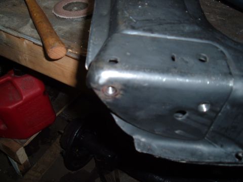 1990 Ford Ranger - A close-up view of a metal component with several bolt holes, possibly part of a vehicle's suspension or frame. A red gas can and a wooden-…