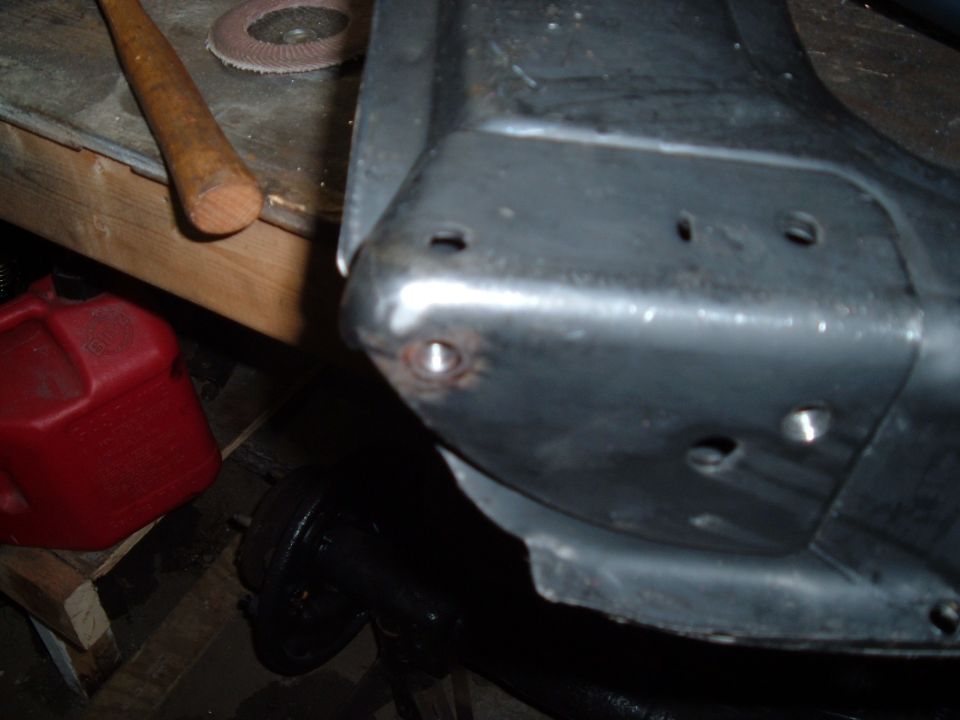 Close-up of a metal vehicle part with bolt holes, red gas can and tool in background.