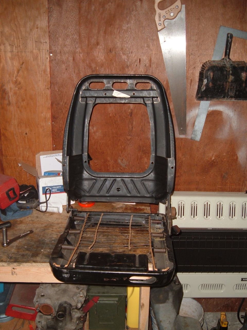 Black car seat base with metal springs in a workshop.