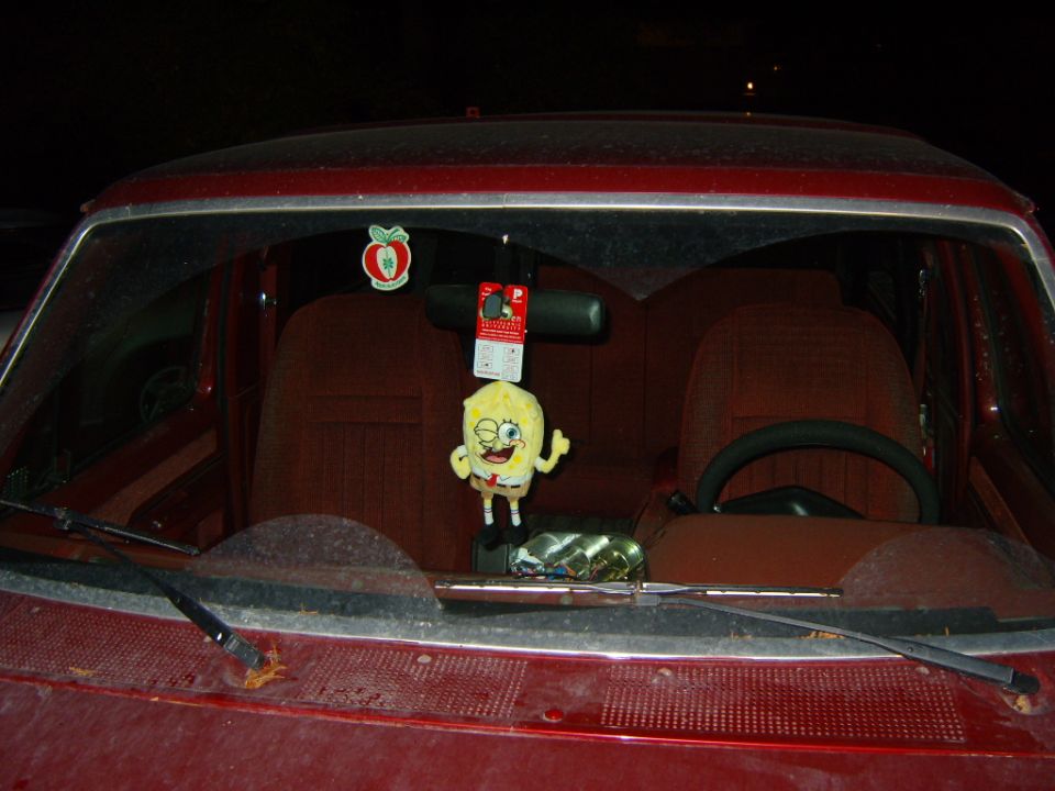Interior of a dark red vehicle, Spongebob plush toy hanging from rearview mirror.