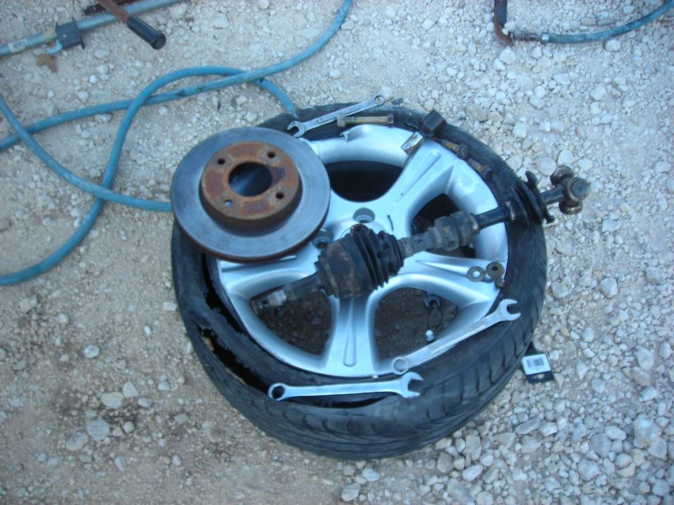 Car wheel, brake rotor, and CV axle on the ground.