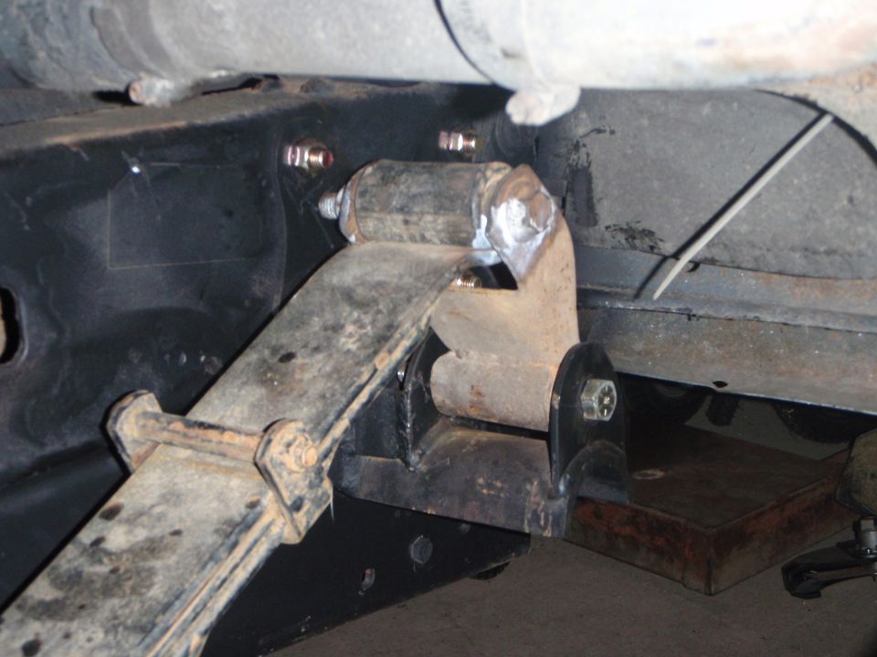 Close-up of vehicle leaf spring and custom bracket modification.