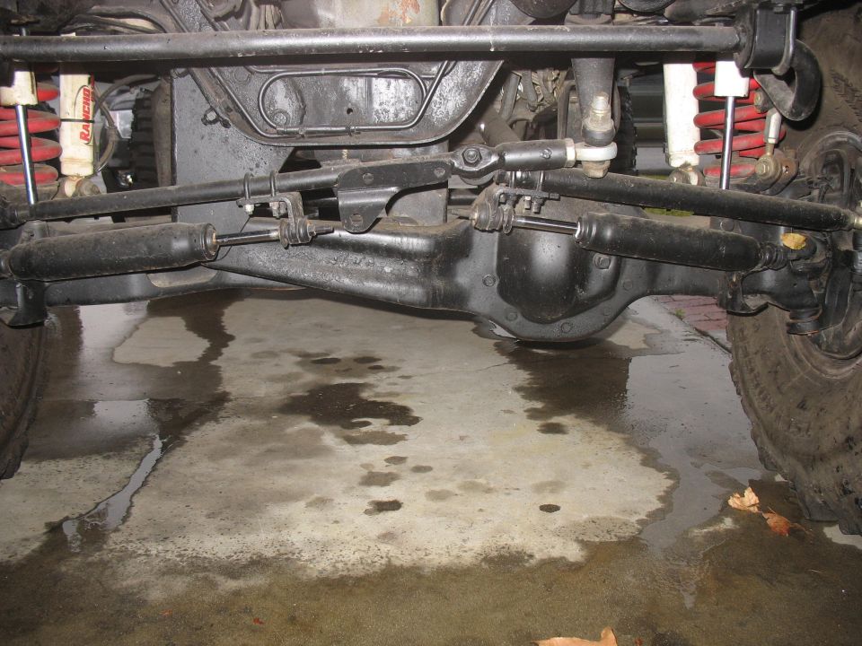 Underside of lifted Bronco showing front axle, dual steering stabilizers, red coils and Rancho shocks