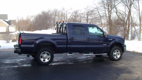 2006 Ford F-350 - A dark blue pickup truck is parked outdoors on a paved surface with snow visible in the background.