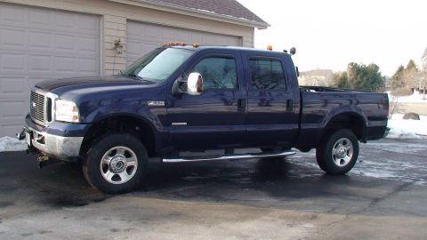 2006 Ford F-350 - Dark blue crew cab pickup truck parked in front of a garage.