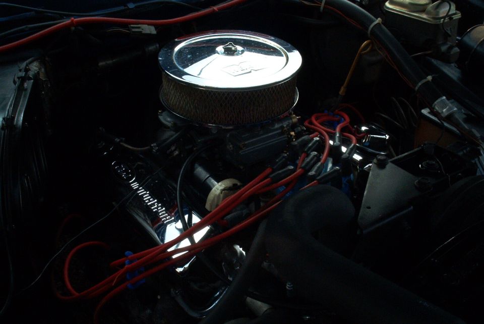 V8 engine bay with chrome round air cleaner, red plug wires and headers