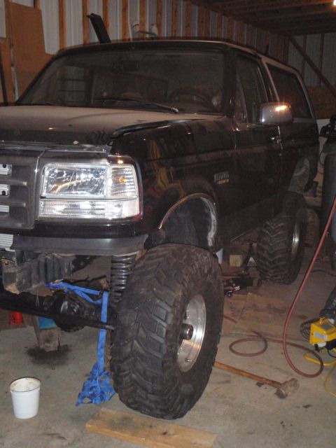 1996 Ford Bronco - A black Ford Bronco is shown from the front 3/4 angle with a large off-road tire mounted on the front passenger side. The vehicle appears t…