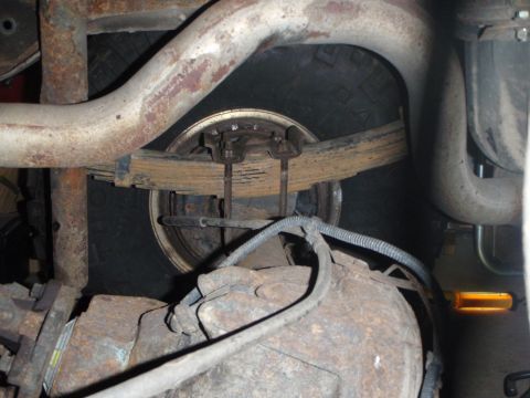 1996 Ford Bronco - This is a close-up, low-angle shot of the underside of a vehicle, focusing on the rear suspension components. Visible parts include leaf sp…