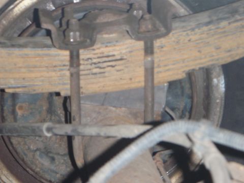 1996 Ford Bronco - This close-up photo shows the underside of a vehicle, specifically focusing on the leaf spring suspension system with U-bolts and threaded…