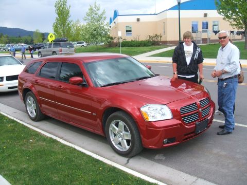 1974 Ford Ranchero - A red Dodge Magnum wagon is parked on the street with two people standing next to it.
