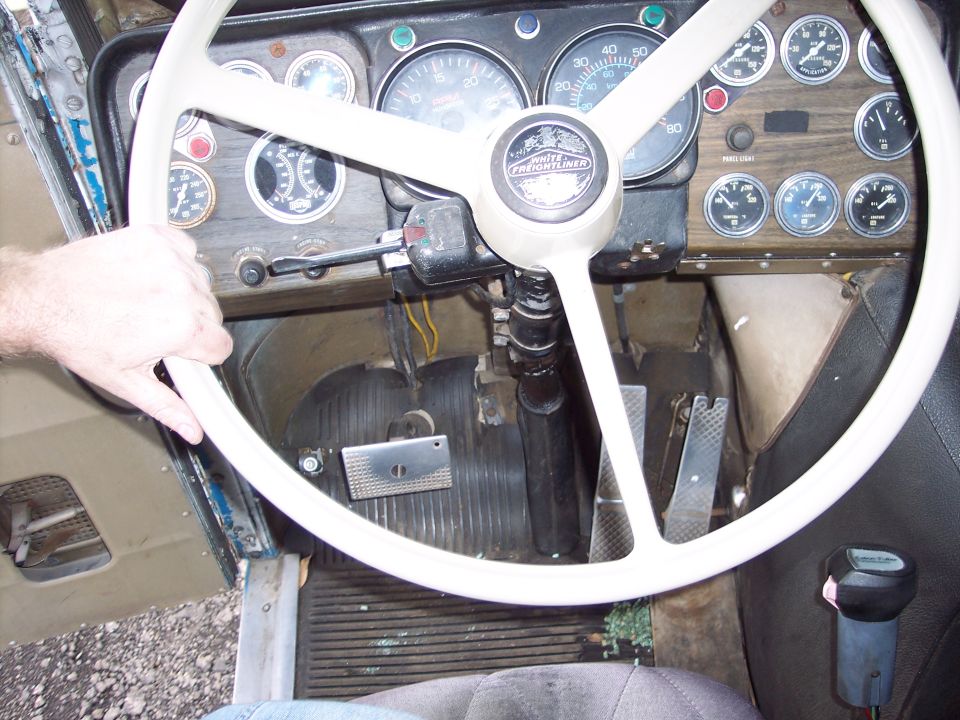 Driver's hand on steering wheel of a truck, dashboard with gauges visible
