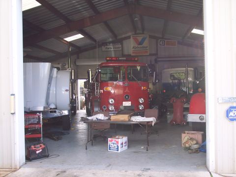 1981 Kenworth W900A - A red fire truck is parked in a garage bay with other vehicles present.