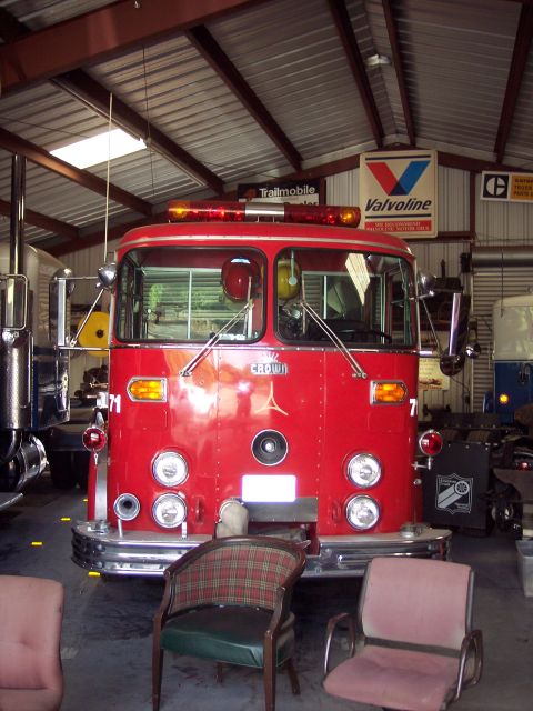 1981 Kenworth W900A - A red fire truck is parked inside a garage with other vehicles and signs on the wall.