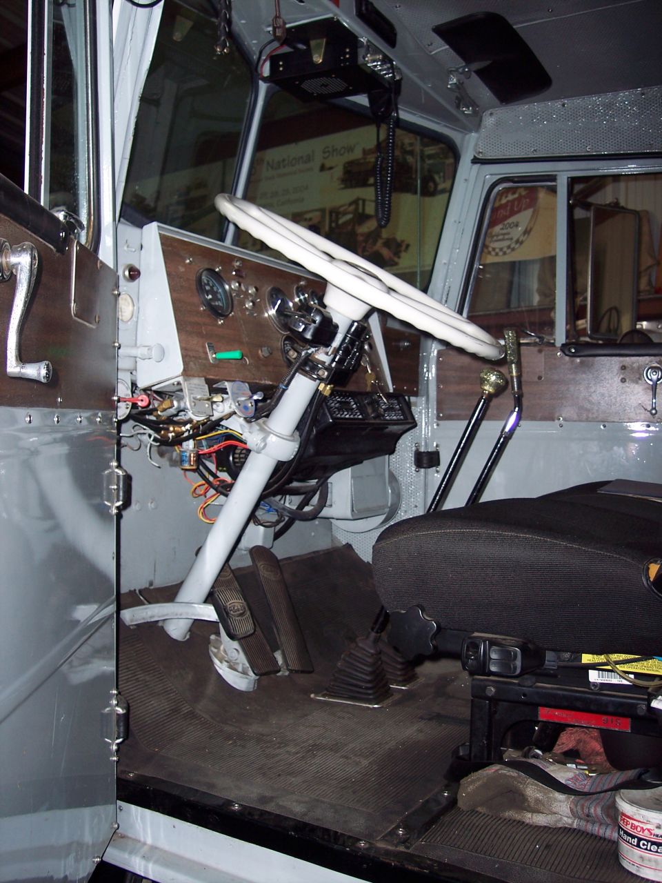 Semi truck cab interior under restoration with white steering wheel and exposed wiring