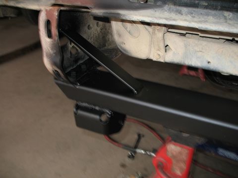 1985 Ford Bronco - This image shows a close-up view of a vehicle's rear bumper mounting bracket, with some red jack stands visible.