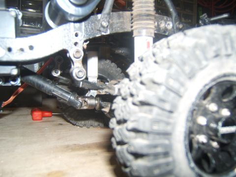1988 Ford Bronco - Detail shot of a remote control crawler's suspension system and a large, knobby tire.