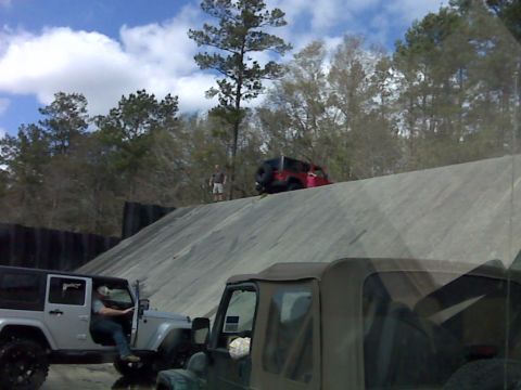 2008 Jeep Wrangler - Two Jeep Wranglers are seen at an off-road park, with one silver model parked and a red one ascending a dirt incline.