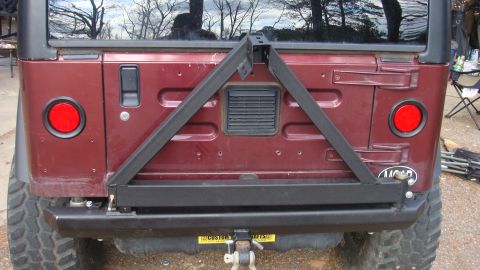 1995 Ford Bronco - The rear of a maroon Jeep Wrangler is shown with a custom tire carrier and bumper assembly.