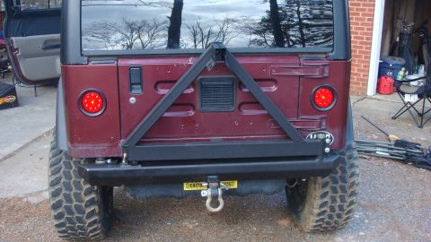 1995 Ford Bronco - Rear view of a maroon Jeep Wrangler, equipped with a spare tire carrier and aftermarket LED tail lights.