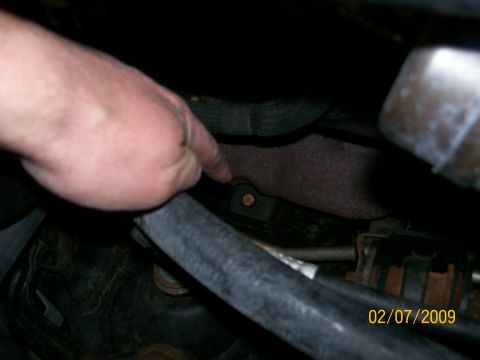 1995 Mercury Grand Marquis - A hand points to a bolt on a rusty engine part, with a date stamp visible in the corner.