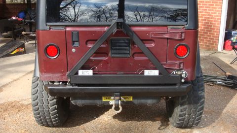 1995 Ford Bronco - The rear of a Jeep Wrangler is shown, a spare tire carrier and aftermarket bumper with a tow hitch.