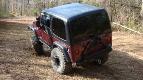 1995 Ford Bronco - A modified Jeep Wrangler is shown from a rear three-quarter view on an outdoor trail.