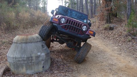 1995 Ford Bronco - This Jeep Wrangler is navigating an off-road obstacle course in a wooded area.