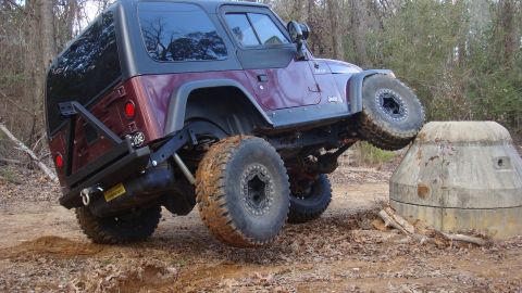 1995 Ford Bronco - This modified Jeep Wrangler TJ is shown off-road, with one wheel elevated as it navigates a concrete structure.