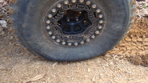 1995 Ford Bronco - Off-road tire and wheel detail on a dirt and mud surface.
