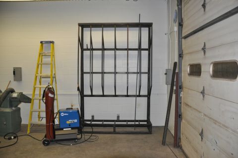 1996 Ford Bronco - A metal rack stands in a garage next to a ladder and welding equipment.