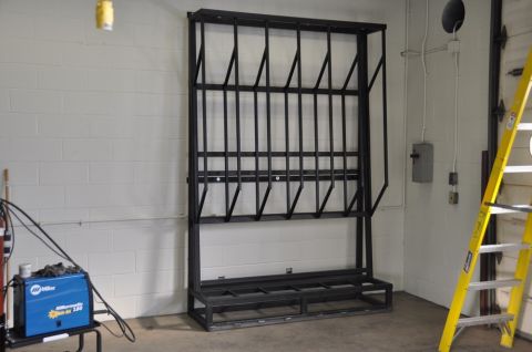 1996 Ford Bronco - A black metal rack designed for storing items vertically is shown in a workshop setting.
