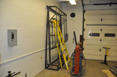 1996 Ford Bronco - A metal rack and welding equipment are stored in a garage bay next to a large overhead door.