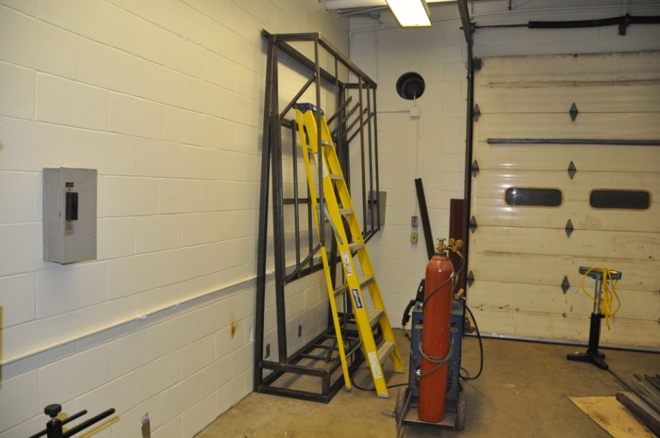 Metal rack with yellow ladder, welding equipment, and garage door