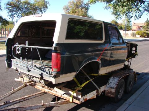1996 Ford Bronco - Ford Bronco body being transported on a trailer, missing its front end components.
