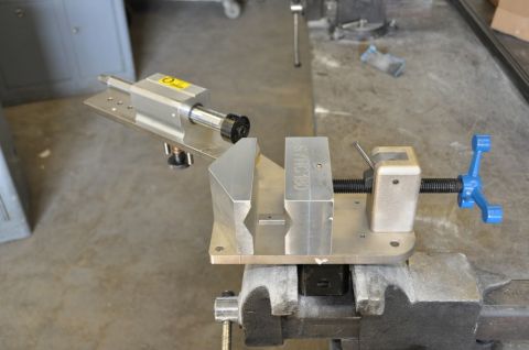 1996 Ford Bronco - A close-up view of a metal vise holding a specialized jig with a spindle and a blue handle.