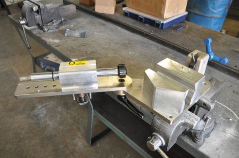 1996 Ford Bronco - A metal jig with vices is secured to a workbench, with a yellow warning sticker visible on the jig.