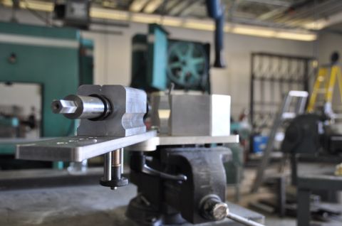 1996 Ford Bronco - Machining jig held in a vise with a workshop background.