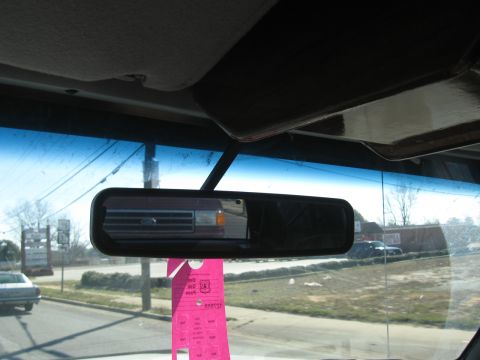 1988 Ford C-350 (Centurion Conversions) - Reflection of a red Ford F-Series truck grille is visible in the rearview mirror, with a pink parking pass hanging below.