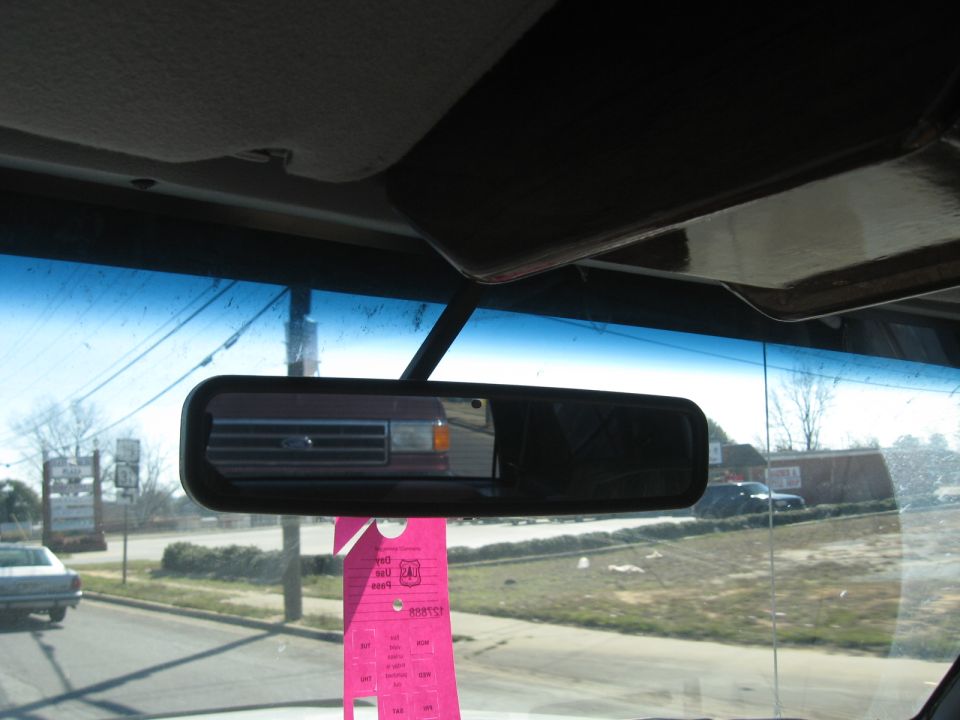 Reflection of a red Ford F-Series truck grille in the rearview mirror