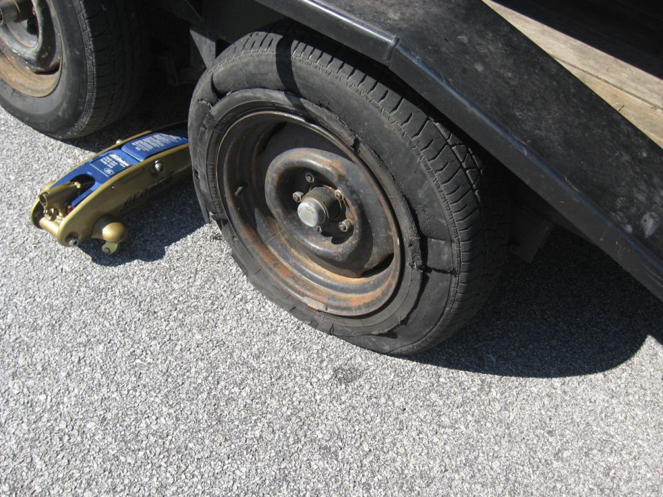 Flat tire next to a blue and gold car jack