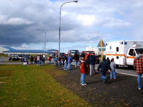 1996 Ford Bronco - An ambulance and other vehicles are present at a scene with a gathering of people under a cloudy sky.