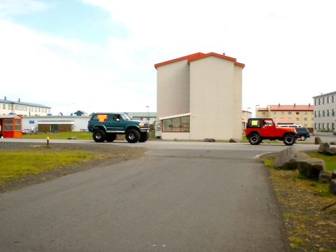 1996 Ford Bronco - Two modified SUVs are parked on a paved area near buildings under a cloudy sky.