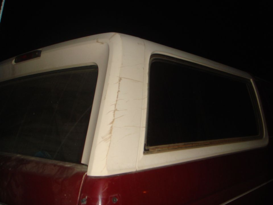 Rear passenger side of a red and white SUV with a white top at night.